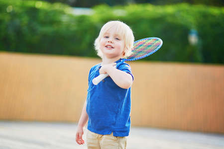 Adorable little boy playing badminton on the playground. Outdoor summer activities for kidsの写真素材