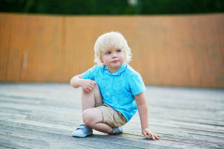 Cute little boy squatting on his haunches on the playgroundの写真素材