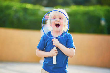Adorable little boy playing badminton on the playground. Outdoor summer activities for kidsの写真素材