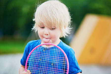 Adorable little boy playing badminton with his mother on the playground. Outdoor summer activities for kids. Family time togetherの写真素材