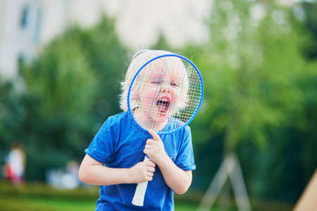 Adorable little boy playing badminton on the playground. Outdoor summer activities for kidsの写真素材