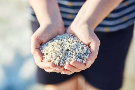 Girl with handful of small white pebbles from "rice beach" Is Arutas in Sardinia, Italyの写真素材