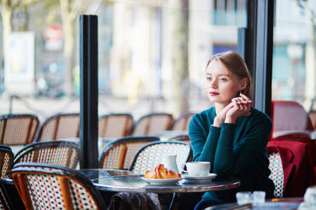 Elegant French woman drinking coffee in Parisian cafe near the windowの写真素材
