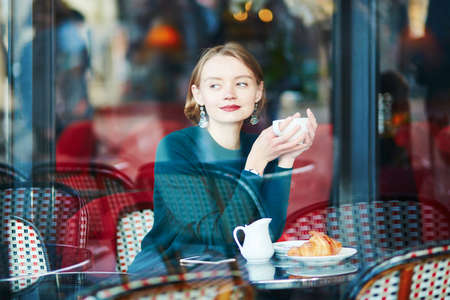 Young elegant woman drinking coffee in traditional cafe in Paris, Franceの写真素材