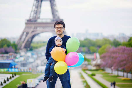 Happy family of two with bunch of colorful balloons in Paris near the Eiffel tower. Father and little son enjoying their vacation in Franceの写真素材