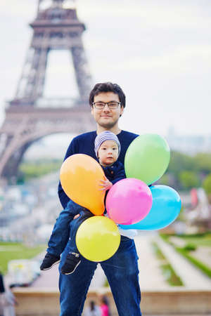 Happy family of two with bunch of colorful balloons in Paris near the Eiffel tower. Father and little son enjoying their vacation in Franceの写真素材