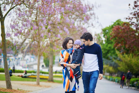 Happy family of three in Paris on a spring day with purple jacarandas in full bloom. Mother, father and little son enjoying their family time and vacation to Franceの写真素材