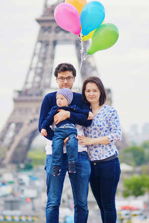 Happy family of three with bunch of colorful balloons in Paris near the Eiffel tower. Mother, father and little son enjoying their vacation in Franceの写真素材