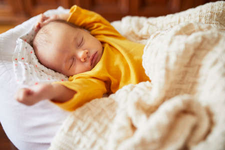 Newborn baby girl sleeping under knitted blanket