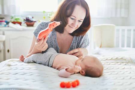 Beautiful woman with her adorable newborn baby girl. Mother and daughter together in bedroom