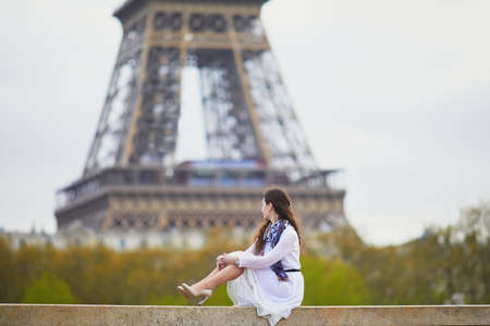 Happy young woman in white dress near the Eiffel tower in Paris, Franceの写真素材