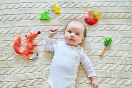 Newborn baby girl playing with colorful rattle toys. Development games for infantsの写真素材