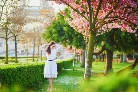 Happy young woman in white dress enjoying cherry blossom season in Paris, Franceの写真素材
