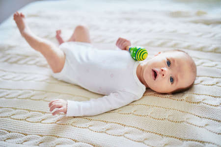 Newborn baby girl playing with colorful rattle toy. Development games for infantsの写真素材