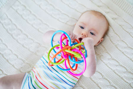 Newborn baby girl playing with colorful toy. Development games for infantsの写真素材