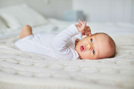 Adorable baby girl lying on bed in nurseryの写真素材