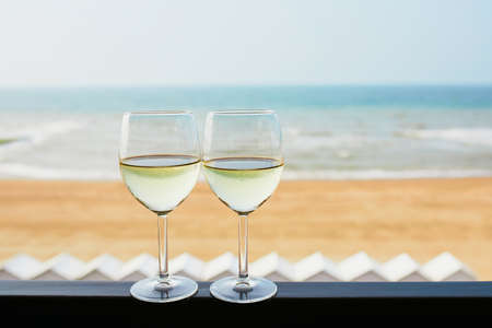 Two glasses of white wine with Atlantic coast beach in background. Normandy, Franceの写真素材