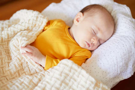 Adorable baby girl sleeping under knitted blanket in nursery