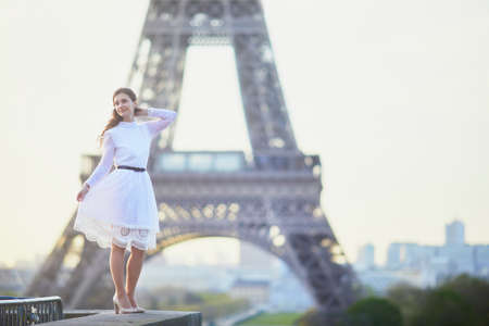 Happy young woman in white dress near the Eiffel tower in Paris, Franceの写真素材