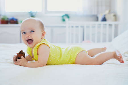 Adorable baby girl with wooden toy. Little child having fun. Infant kid in sunny nursery