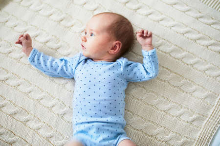 Adorable baby girl lying on bed. Infant kid in sunny nursery