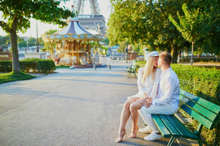 Happy couple near the Eiffel tower. Tourists enjoying their vacation in France. Romantic date or traveling couple conceptの写真素材