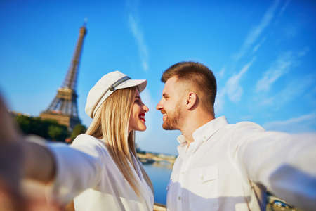 Happy couple taking selfie near the Eiffel tower. Tourists enjoying their vacation in France. Romantic date or traveling couple conceptの写真素材