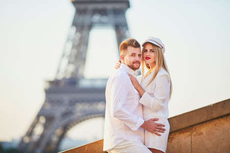 Happy couple near the Eiffel tower. Tourists enjoying their vacation in France. Romantic date or traveling couple conceptの写真素材