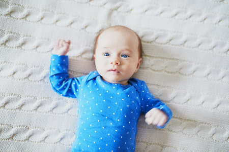 Adorable baby girl lying on bed. Infant kid in sunny nursery