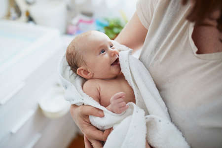 Mother holding little baby wrapped in towel after bathの写真素材