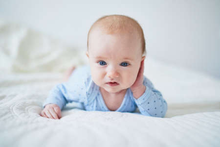 Baby girl learning to crawl. Little child doing tummy time. Infant kid in sunny nursery