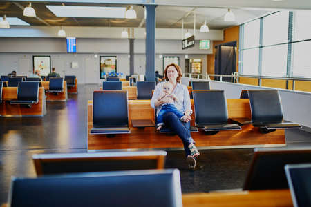 Woman with little girl in international airport. Mother with baby waiting for their flight....