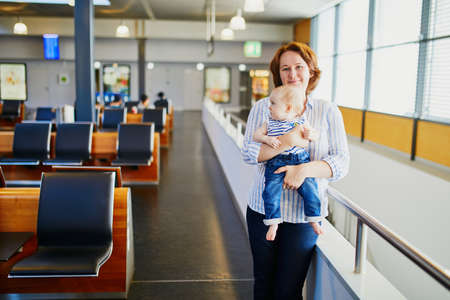 Woman with little girl in international airport. Mother with baby waiting for their flight. Travelling with kidsの写真素材