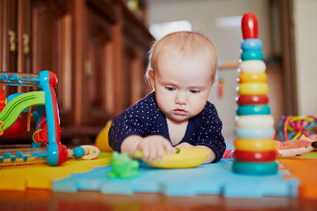 Baby girl playing with toys on the floor. Happy healthy little child at homeの写真素材