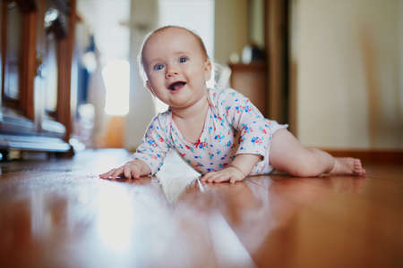 Baby girl learning to crawl. Happy healthy little child on the floor. Infant kid at home