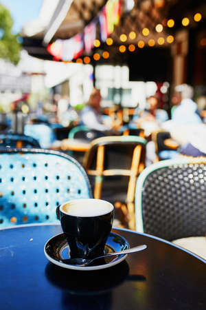 Cup of coffee on the table of traditional French street cafe in Paris, France