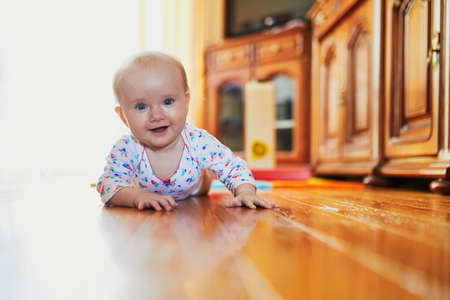 Baby girl learning to crawl. Happy healthy little child on the floor. Infant kid at home