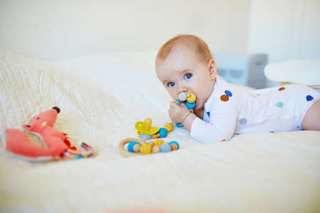 Adorable baby girl relaxing in nursery with toys