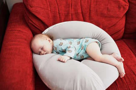 Cute adorable baby girl sleeping on breastfeeding pillow at home