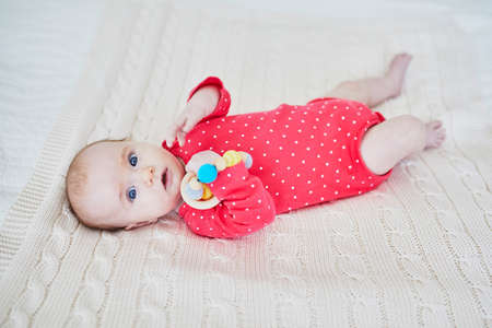 Adorable baby girl in pink bodysuit lying on bed. Happy healthy little child laughing. Infant kid in...