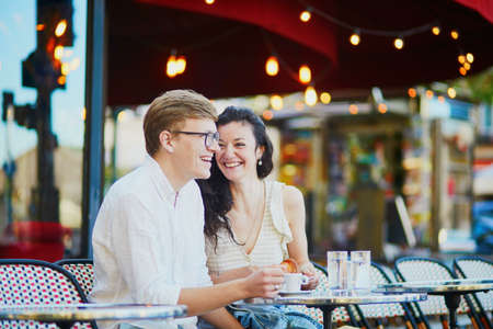Happy romantic couple in Paris, drinking coffee in traditional Parisian outdoor cafe. Tourists spending their vacation in Franceの写真素材