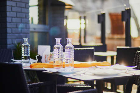 Water bottles and traditional French bread (baguette) on the table of outdoor cafe or restaurant in Etretat with view to the famous cliffs. Seine-Maritime department of Normandy in Franceの写真素材