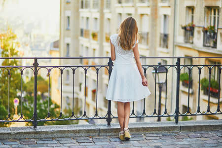 Beautiful young woman in white dress walking on famous Montmartre hill in Paris, France at early morningの写真素材