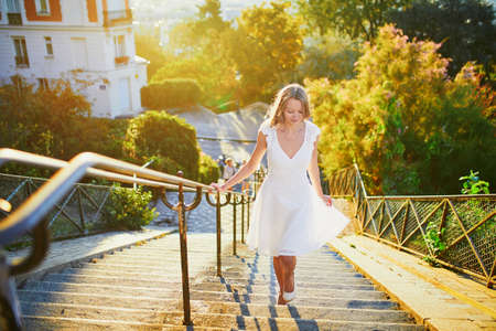 Beautiful young woman in white dress walking on famous Montmartre hill in Paris, France at early...