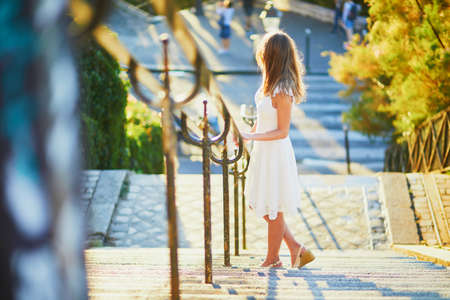 Beautiful young woman in white dress walking on famous Montmartre hill in Paris, France at early...