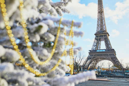 Christmas tree covered with snow and decorated with beads near the Eiffel tower in Paris....