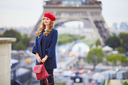 Young woman with long blond curly hair in Paris, France. Beautiful tourist in red beret near the Eiffel towerの写真素材