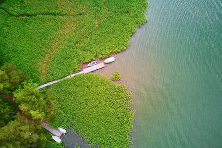 Scenic aerial view of lake house with wooden berth surrounded by pine forest in the countryside of Finlandの写真素材