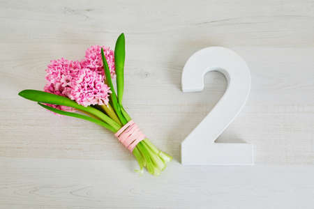 Bunch of pink hyacinths and white wooden number two. Second birthday or anniversary concept