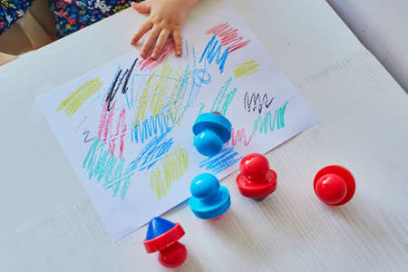 Little child drawing with wax pencils at home, in kindergaten or preschool. Creative games for kids